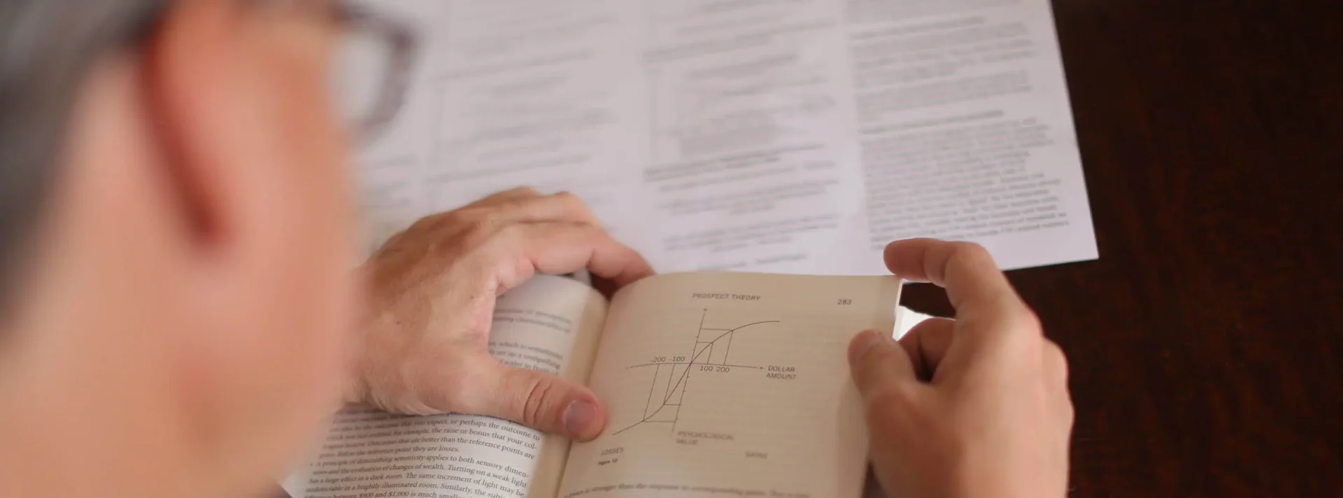 A person holding an open book with a pen and paper.